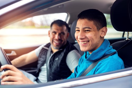 teen boy driving with father